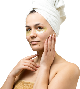 Kafasında beyaz havluyla gezen genç bir kız gözlerinin altına kolajen jel bantlar takıyor. Göz teması altında maske.