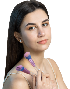 Açık renk bluzlu, beyaz arka planda yüz makyajı yapan genç bir kızın yakın çekimi. Güzel bir kadın yüzüne bir makyaj fırçası tutar ve gülümser..