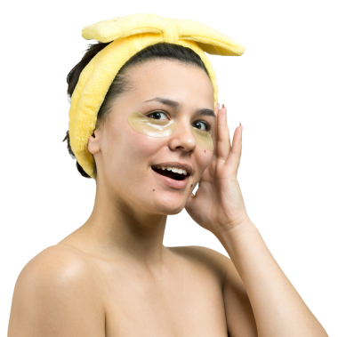 Kafasında beyaz havluyla gezen genç bir kız gözlerinin altına kolajen jel bantlar takıyor. Göz teması altında maske.