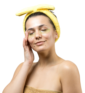 Kafasında beyaz havluyla gezen genç bir kız gözlerinin altına kolajen jel bantlar takıyor. Göz teması altında maske.