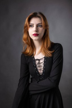 Stüdyoda kasvetli bir geçmişi olan siyah elbiseli kızıl saçlı gotik kız..