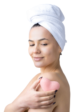 Kafasında beyaz havluyla güzel bir kadın portresi ve pembe bir kalbe bakan bir vücut için sünger. Cilt temizleme eko organik kozmetik rahatlama konsepti.