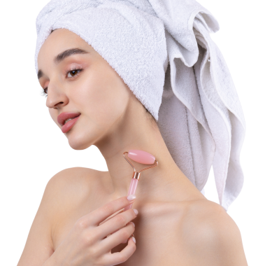 Kalın kaşlı güzel bir kız, beyaz arka planda mükemmel bir ten, kafasında havlu, güzel bir fotoğraf. Kozmetik rulo tutuyor..