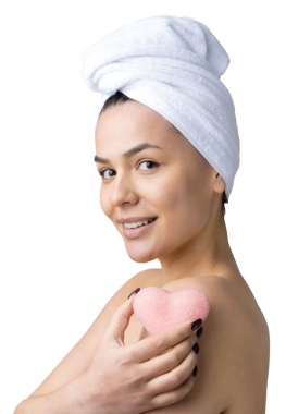 Kafasında beyaz havluyla güzel bir kadın portresi ve pembe bir kalbe bakan bir vücut için sünger. Cilt temizleme eko organik kozmetik rahatlama konsepti.