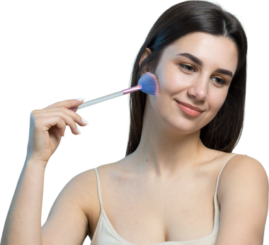 Açık renk bluzlu, beyaz arka planda yüz makyajı yapan genç bir kızın yakın çekimi. Güzel bir kadın yüzüne bir makyaj fırçası tutar ve gülümser..