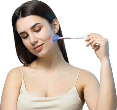 Açık renk bluzlu, beyaz arka planda yüz makyajı yapan genç bir kızın yakın çekimi. Güzel bir kadın yüzüne bir makyaj fırçası tutar ve gülümser..