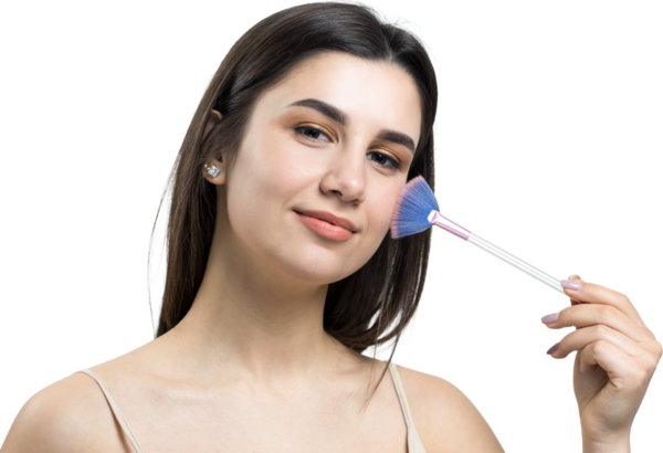 Açık renk bluzlu, beyaz arka planda yüz makyajı yapan genç bir kızın yakın çekimi. Güzel bir kadın yüzüne bir makyaj fırçası tutar ve gülümser..