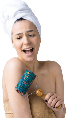 Kafasında havlu olan esmer, gri arka planda izole edilmiş yüz masajı için silindir kullanıyor.