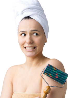 Kafasında havlu olan esmer, gri arka planda izole edilmiş yüz masajı için silindir kullanıyor.