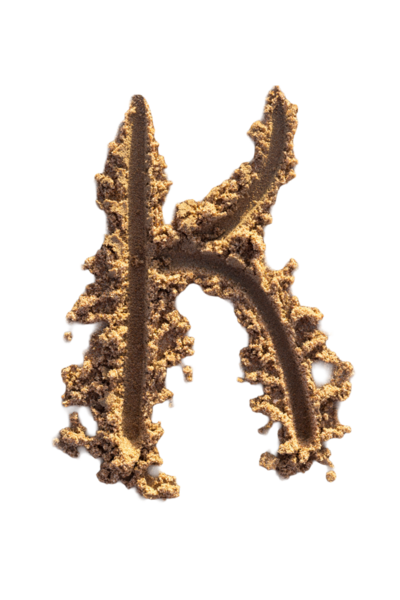 Alfabe (K) harfleri kumsalda el yazısıyla yazılmış.