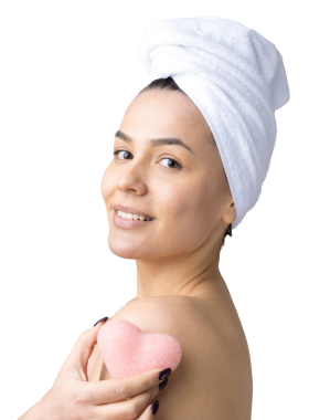 Kafasında beyaz havluyla güzel bir kadın portresi ve pembe bir kalbe bakan bir vücut için sünger. Cilt temizleme eko organik kozmetik rahatlama konsepti.