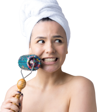 Kafasında havlu olan esmer, gri arka planda izole edilmiş yüz masajı için silindir kullanıyor.