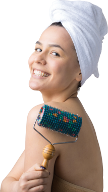 Kafasında havlu olan esmer, gri arka planda izole edilmiş yüz masajı için silindir kullanıyor.