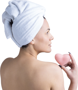 Kafasında beyaz havluyla güzel bir kadın portresi ve pembe bir kalbe bakan bir vücut için sünger. Cilt temizleme eko organik kozmetik rahatlama konsepti.