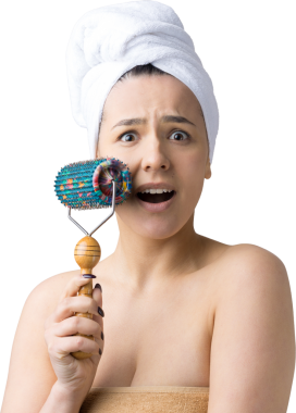 Kafasında havlu olan esmer, gri arka planda izole edilmiş yüz masajı için silindir kullanıyor.