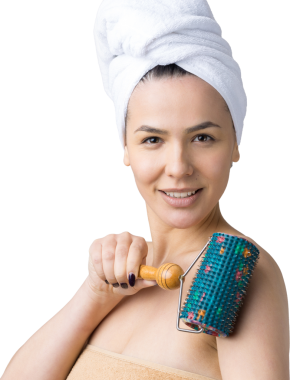 Kafasında havlu olan esmer, gri arka planda izole edilmiş yüz masajı için silindir kullanıyor.