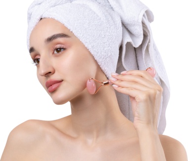 Kalın kaşlı güzel bir kız, beyaz arka planda mükemmel bir ten, kafasında havlu, güzel bir fotoğraf. Kozmetik rulo tutuyor..