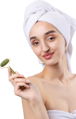 Kalın kaşlı güzel bir kız, beyaz arka planda mükemmel bir ten, kafasında havlu, güzel bir fotoğraf. Kozmetik rulo tutuyor..