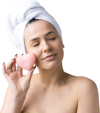 Kafasında beyaz havluyla güzel bir kadın portresi ve pembe bir kalbe bakan bir vücut için sünger. Cilt temizleme eko organik kozmetik rahatlama konsepti.