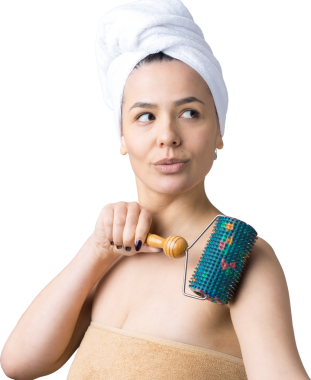 Kafasında havlu olan esmer, gri arka planda izole edilmiş yüz masajı için silindir kullanıyor.