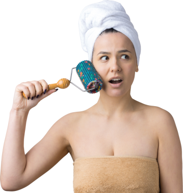 Kafasında havlu olan esmer, gri arka planda izole edilmiş yüz masajı için silindir kullanıyor.