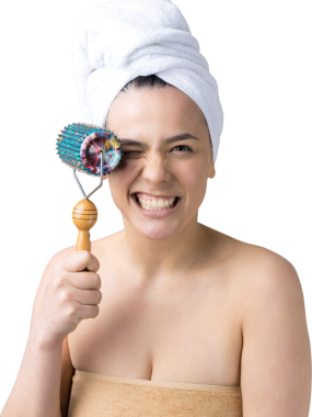 Kafasında havlu olan esmer, gri arka planda izole edilmiş yüz masajı için silindir kullanıyor.