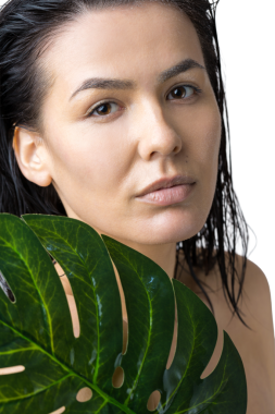 Doğal yeşil palmiye yaprağı portresi olan bir kadın. Moda, güzellik, makyaj, kozmetik.