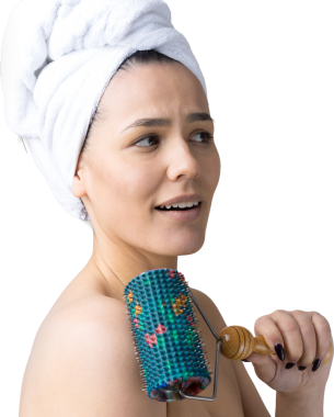 Kafasında havlu olan esmer, gri arka planda izole edilmiş yüz masajı için silindir kullanıyor.