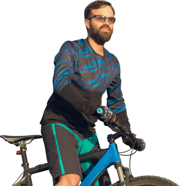 Taze yeşil yaz ormanının arka planına karşı bir uçurumun üzerinde duran bir hava süspansiyon çatal ile modern bir karbon hardtail bisiklet üzerinde şort ve mayo Bisikletçi