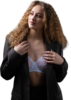 Stüdyoda uzun saçlı, ceketli, kızıl saçlı, kıvırcık bir kızın portresi. Kıvrımlı göğüslerini sütyen içinde gösteriyor..