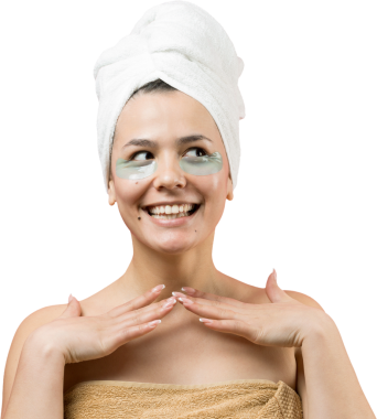 Kafasında beyaz havluyla gezen genç bir kız gözlerinin altına kolajen jel bantlar takıyor. Göz teması altında maske.