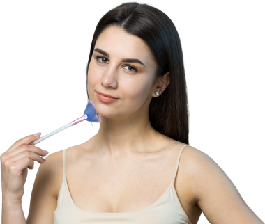 Açık renk bluzlu, beyaz arka planda yüz makyajı yapan genç bir kızın yakın çekimi. Güzel bir kadın yüzüne bir makyaj fırçası tutar ve gülümser..