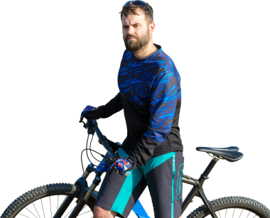 Şortlu ve formalı bisikletçi, modern karbon kuyruklu motorsikletli. Uçurumun kenarında, yeşil bahar ormanlarının arka planında duran bir hava süspansiyon çatalı var.