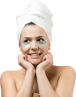 Kafasında beyaz havluyla gezen genç bir kız gözlerinin altına kolajen jel bantlar takıyor. Göz teması altında maske.