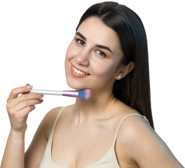 Açık renk bluzlu, beyaz arka planda yüz makyajı yapan genç bir kızın yakın çekimi. Güzel bir kadın yüzüne bir makyaj fırçası tutar ve gülümser..