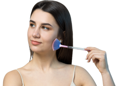 Açık renk bluzlu, beyaz arka planda yüz makyajı yapan genç bir kızın yakın çekimi. Güzel bir kadın yüzüne bir makyaj fırçası tutar ve gülümser..