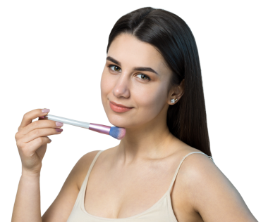 Açık renk bluzlu, beyaz arka planda yüz makyajı yapan genç bir kızın yakın çekimi. Güzel bir kadın yüzüne bir makyaj fırçası tutar ve gülümser..