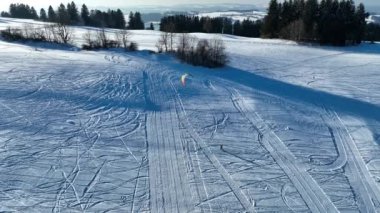 Kışın karda uçan bir uçurtmacının drone videosu. Dağlarda kar yağıyor.