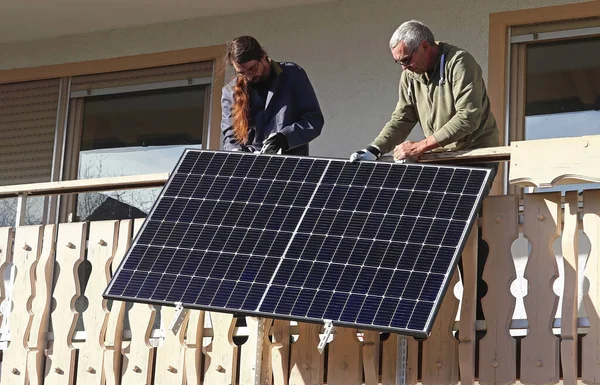 Two men assemble a balcony power plant to generate electricity