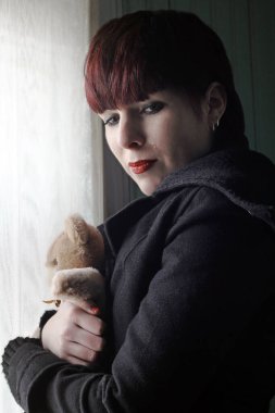Kollarında oyuncak ayıyla ağlayan genç bir kadın.