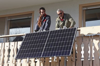 İki adam elektrik üretmek için bir balkon santrali kuruyor.
