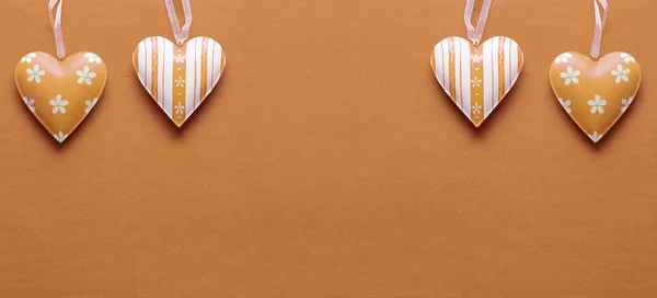 Two metal hearts in Peach Fuzz on a paper background