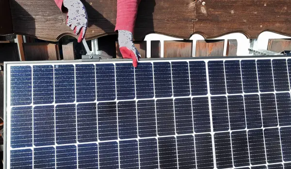 A woman installs a solar system to generate electricity on a balcony