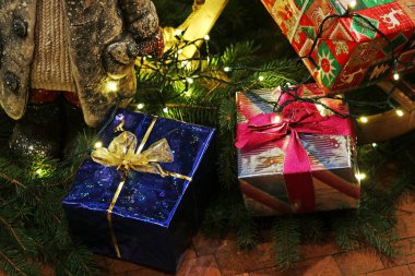 Renkli paketlenmiş Noel hediyeleri ve Noel ağacının altında peri ışıkları