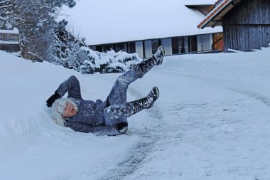 Kışın kaygan bir yolda kayma riski. Bir kadın kayıp kara düşmüş.