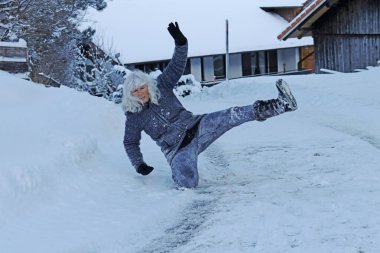 Kışın kaygan bir yolda kayma riski. Bir kadın kayıp kara düşmüş.