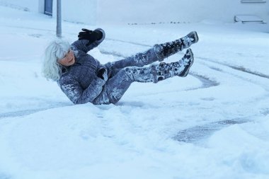 Kışın kaygan bir yolda kayma riski. Bir kadın kayıp kara düşmüş.