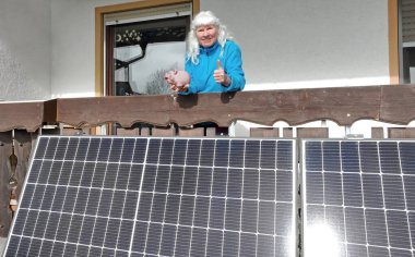 Balkon güç santralinin önünde kumbarası olan bir kadın. Küçük bir fotovoltaik sistem ile para biriktirmek