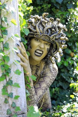 Medusa gibi giyinmiş, yılan kafası ve pençeli elleri olan bir kadın.