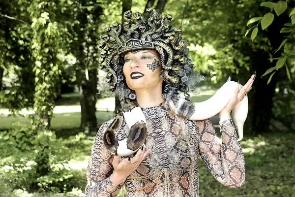 Medusa gibi giyinmiş, boynunda yılan olan bir kadın.
